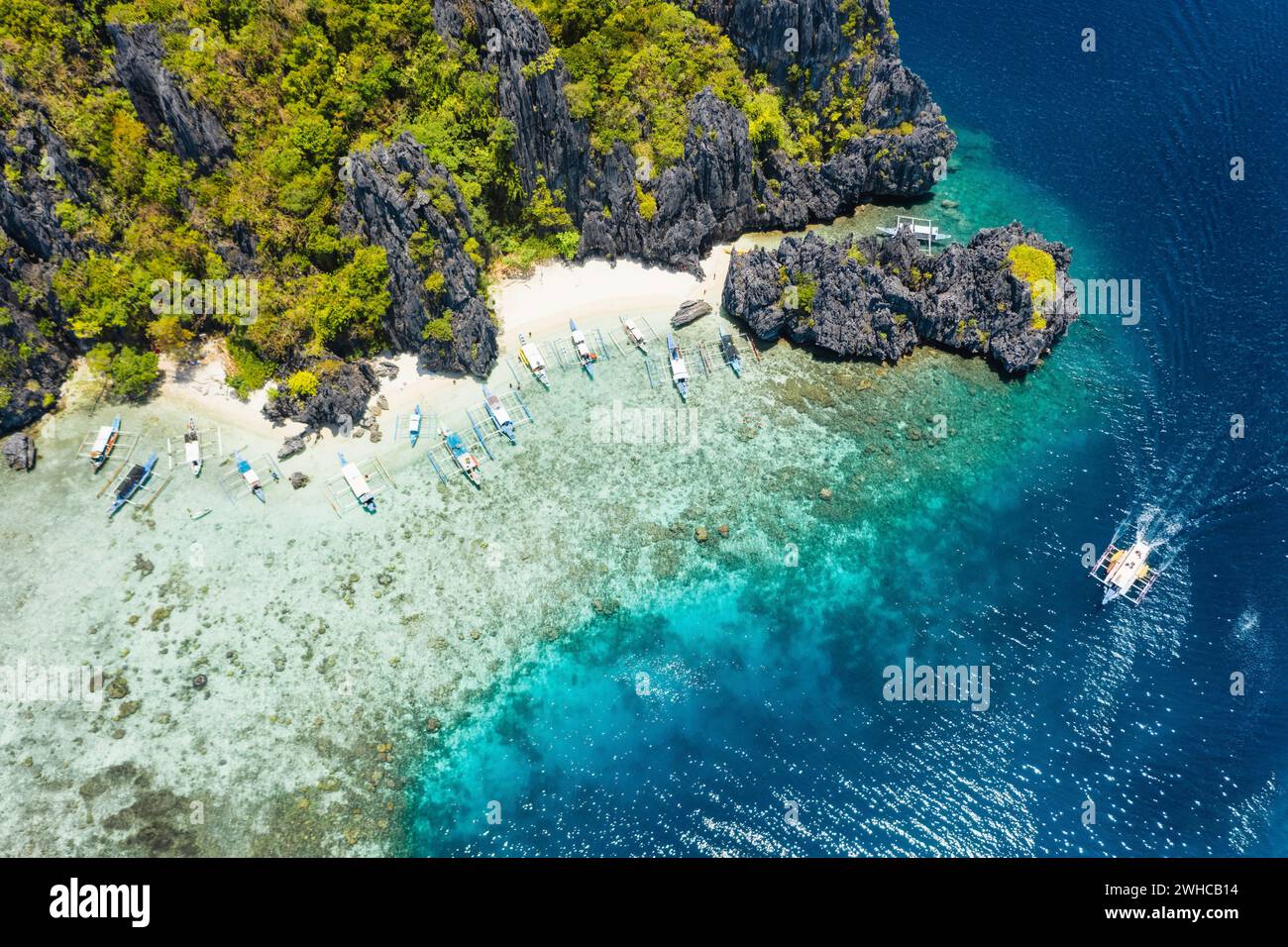 Vista aérea de drones barcos turísticos amarrados en la isla tropical Shimizu. Rocas costeras de piedra caliza, playa de arena blanca en agua azul. El Nido, Palawan, Filipinas. Foto de stock