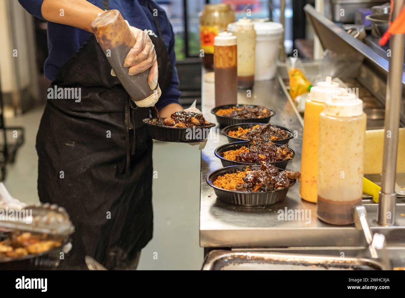 Detroit, Michigan - Los trabajadores preparan comida en el restaurante Yum Village, que sirve comidas afrocaribeñas. Foto de stock