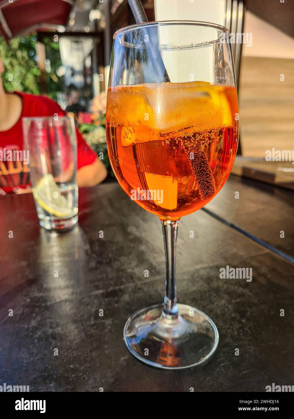 El refresco alcohólico Aperol Spritz se coloca en una mesa junto a un vaso de agua mineral Foto de stock