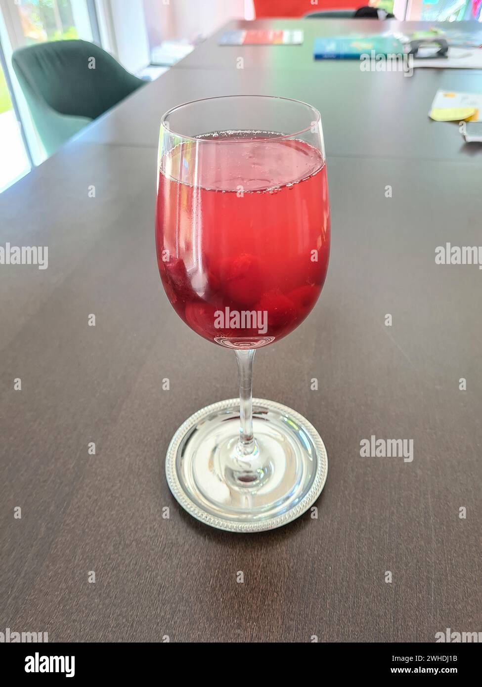 Cóctel sin alcohol Wild Berries Dreams servido en una copa de vino en la mesa al final del día Foto de stock