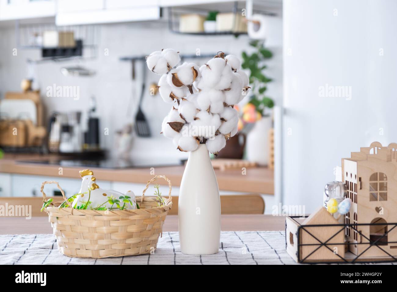 Decoración de Pascua de huevos de colores en una cesta y un pollo en la mesa de la cocina en un estilo rústico. Interior festivo de un conde Foto de stock