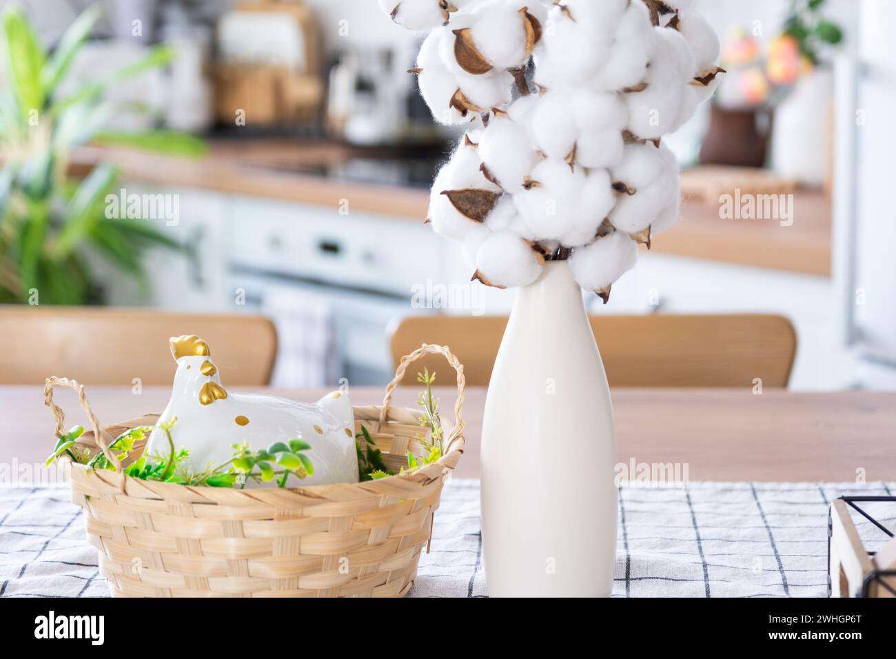 Decoración de Pascua de huevos de colores en una cesta y un pollo en la mesa de la cocina en un estilo rústico. Interior festivo de un conde Foto de stock