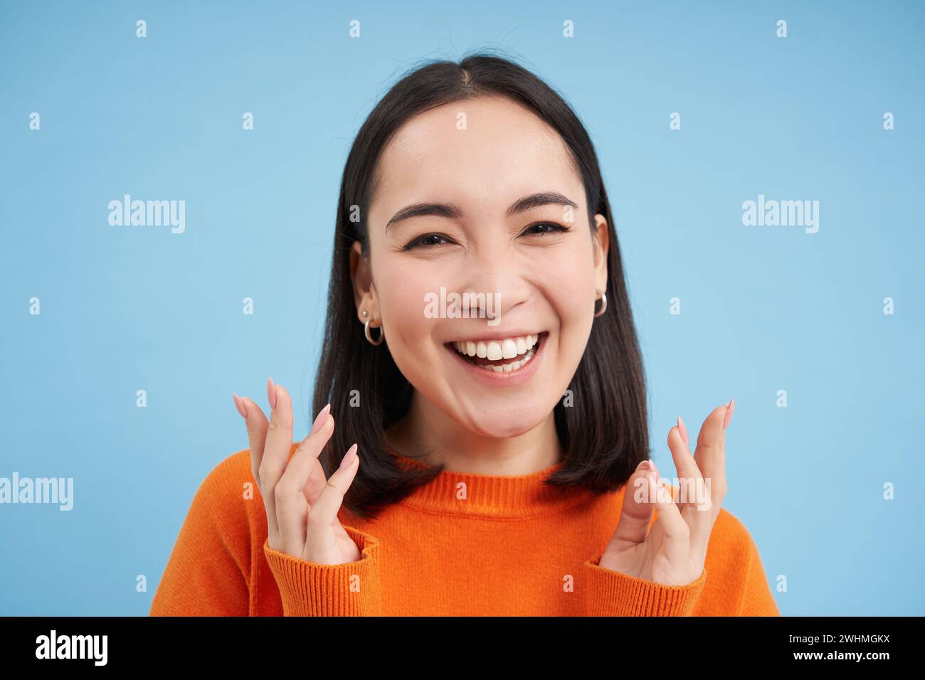 Close up retrato de chica asiática con sonrisa sana perfecta y cara hermosa natural, se ve feliz en la cámara, se coloca sobre azul b Foto de stock