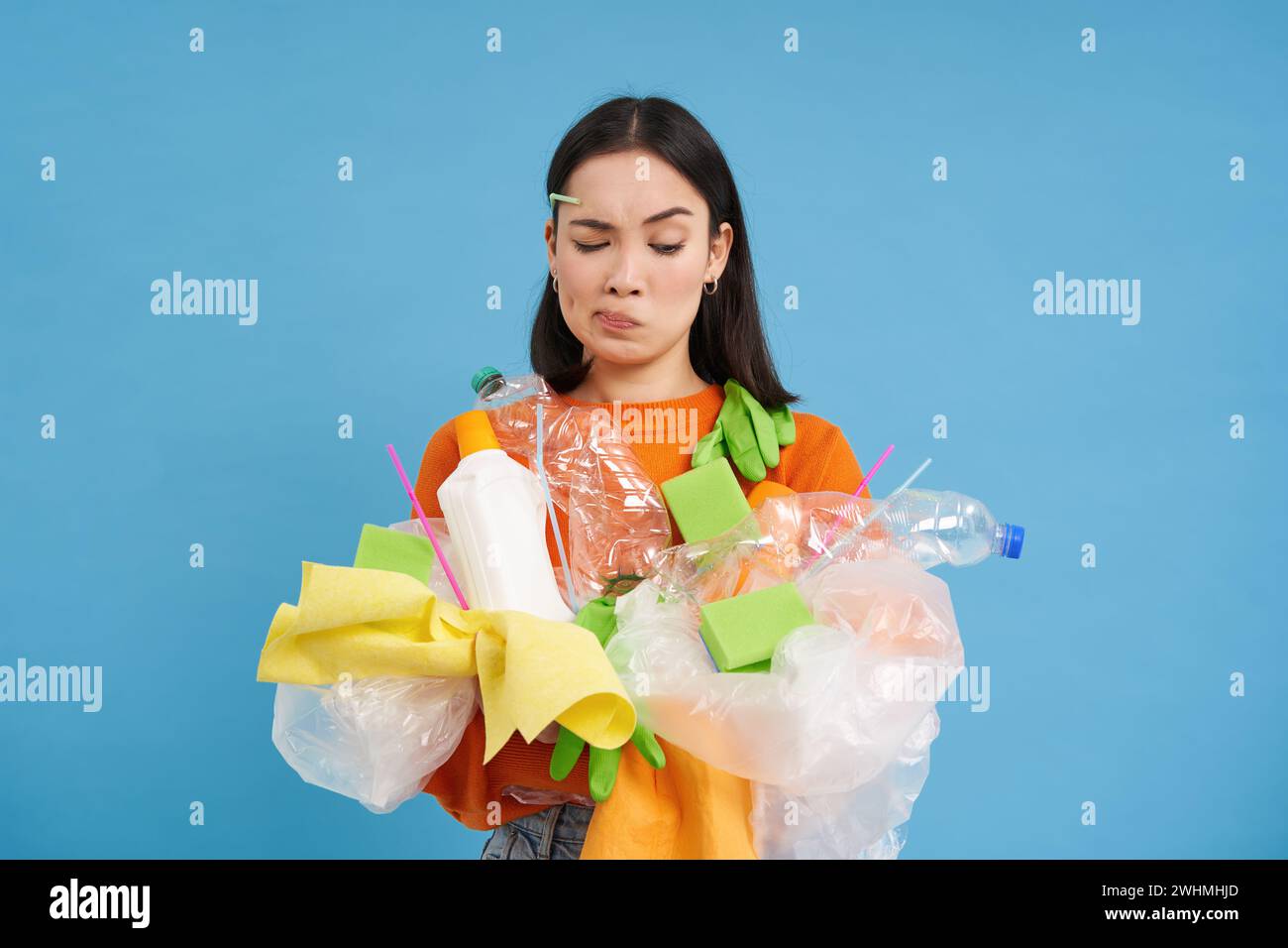 El cuidado de la naturaleza. Mujer joven sosteniendo botellas de plástico y residuos. Los voluntarios compilaron basura y la llevaron al reciclaje. azul es Foto de stock