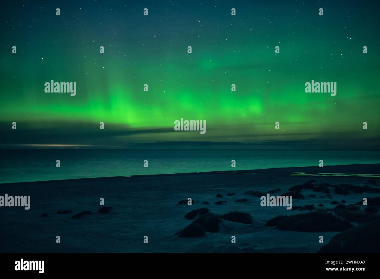 Luces boreales verdes bailando sobre la playa Foto de stock