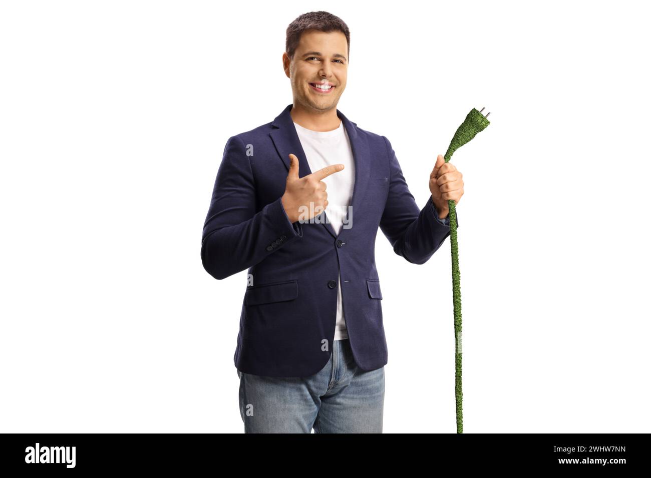 Hombre joven feliz apuntando a un cable eléctrico verde aislado sobre fondo blanco Foto de stock