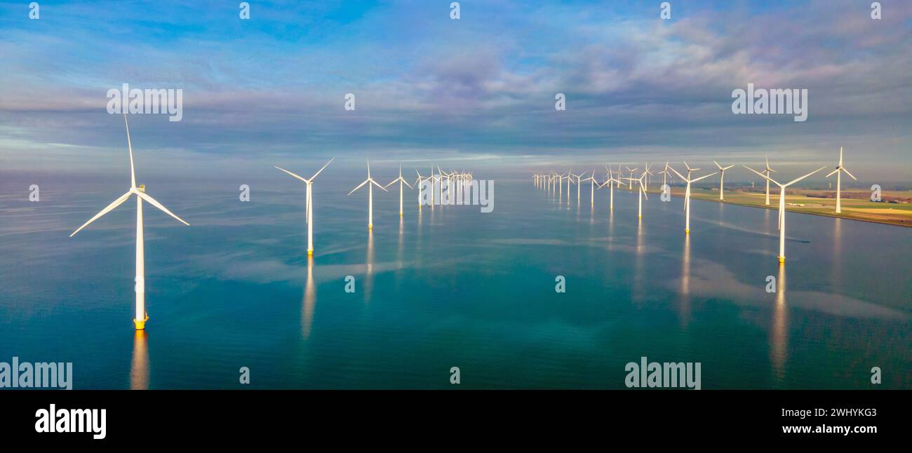 Turbinas de molino de viento en el mar visto desde una vista aérea de drones desde arriba en un enorme parque de molinos de viento Foto de stock