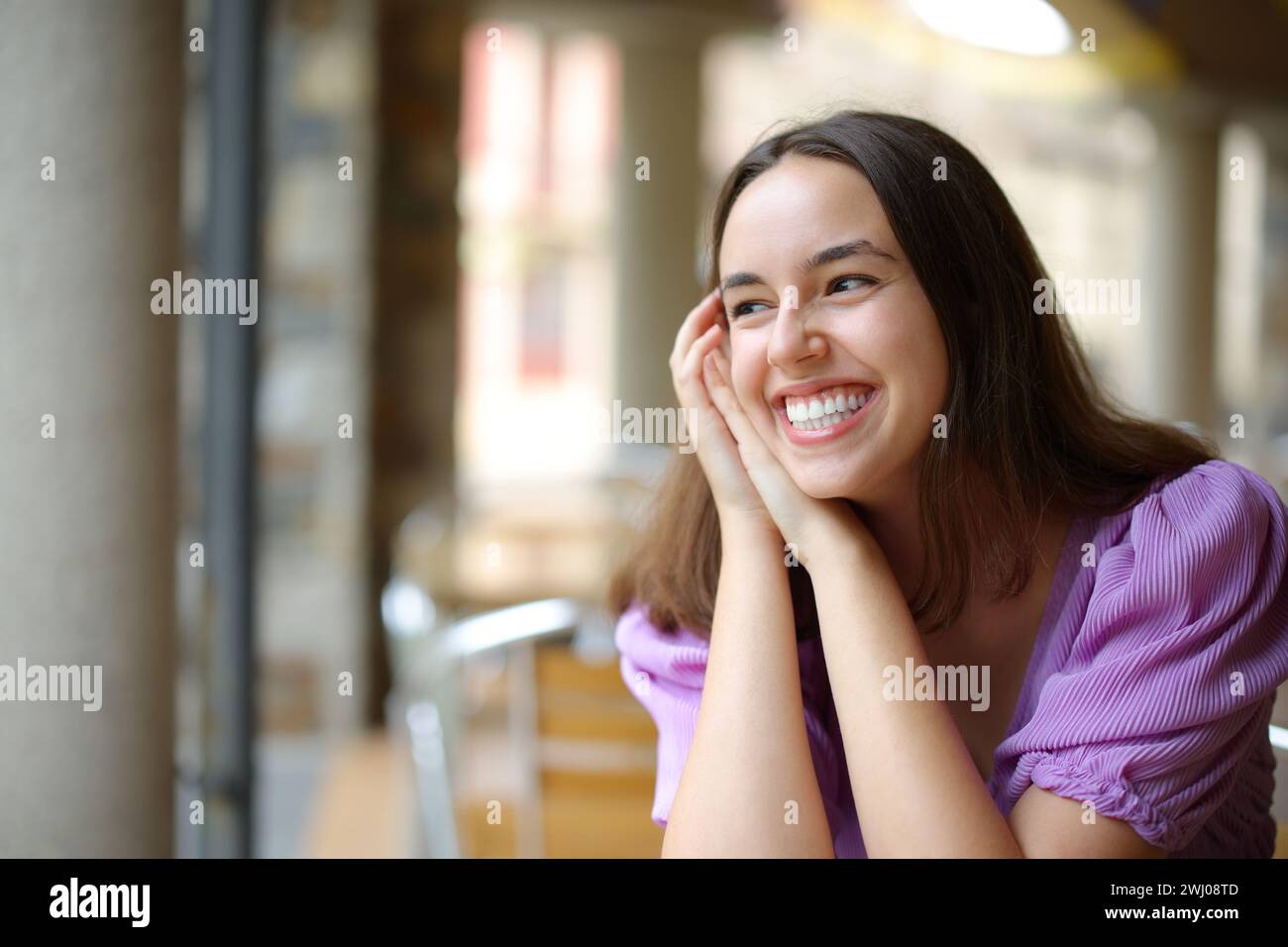 Mujer feliz riendo sola en un bar mirando a un lado Foto de stock