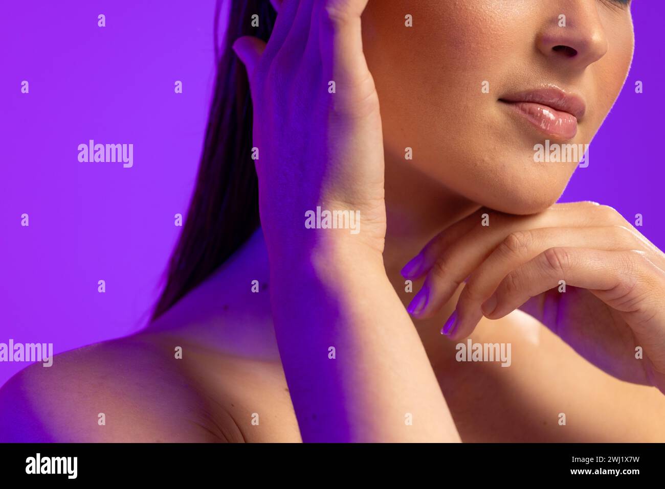 Mujer caucásica que lleva el brillo claro del labio sobre fondo púrpura Foto de stock