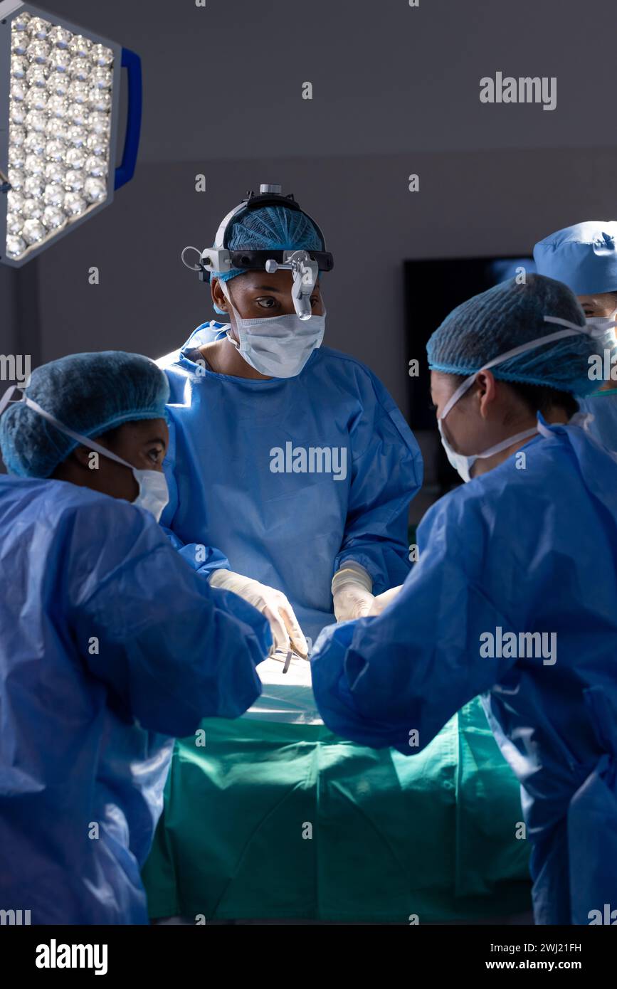 Diversas mujeres médicas con máscaras faciales haciendo cirugía en el quirófano del hospital Foto de stock