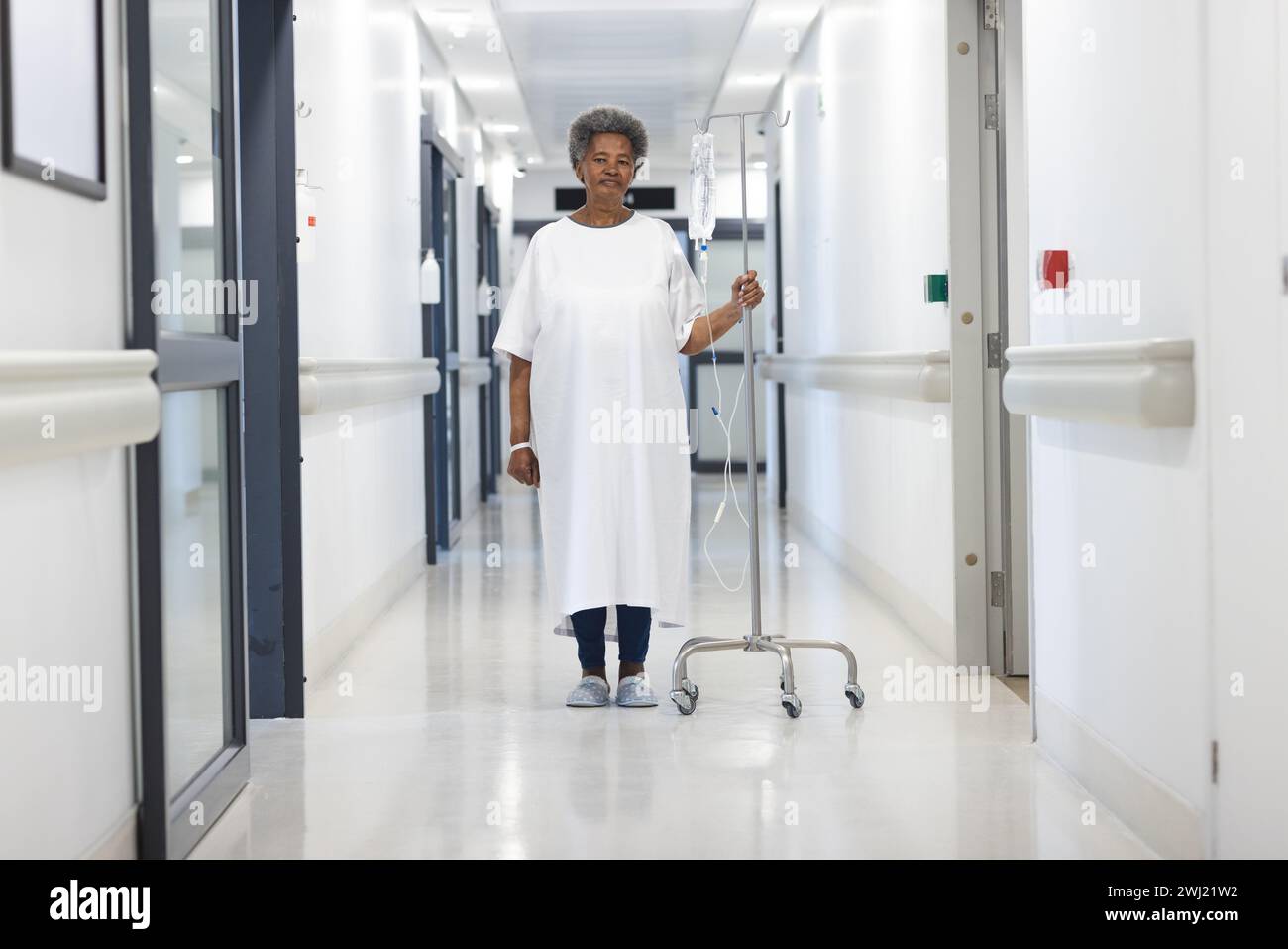 Paciente afroamericana mayor femenina con goteo de pie en pasillo hospitalario Foto de stock