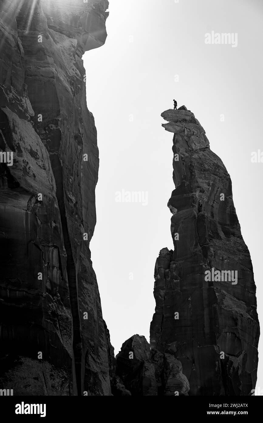 Vista de ángulo bajo del montañero de pie en el pico del acantilado contra el cielo Foto de stock