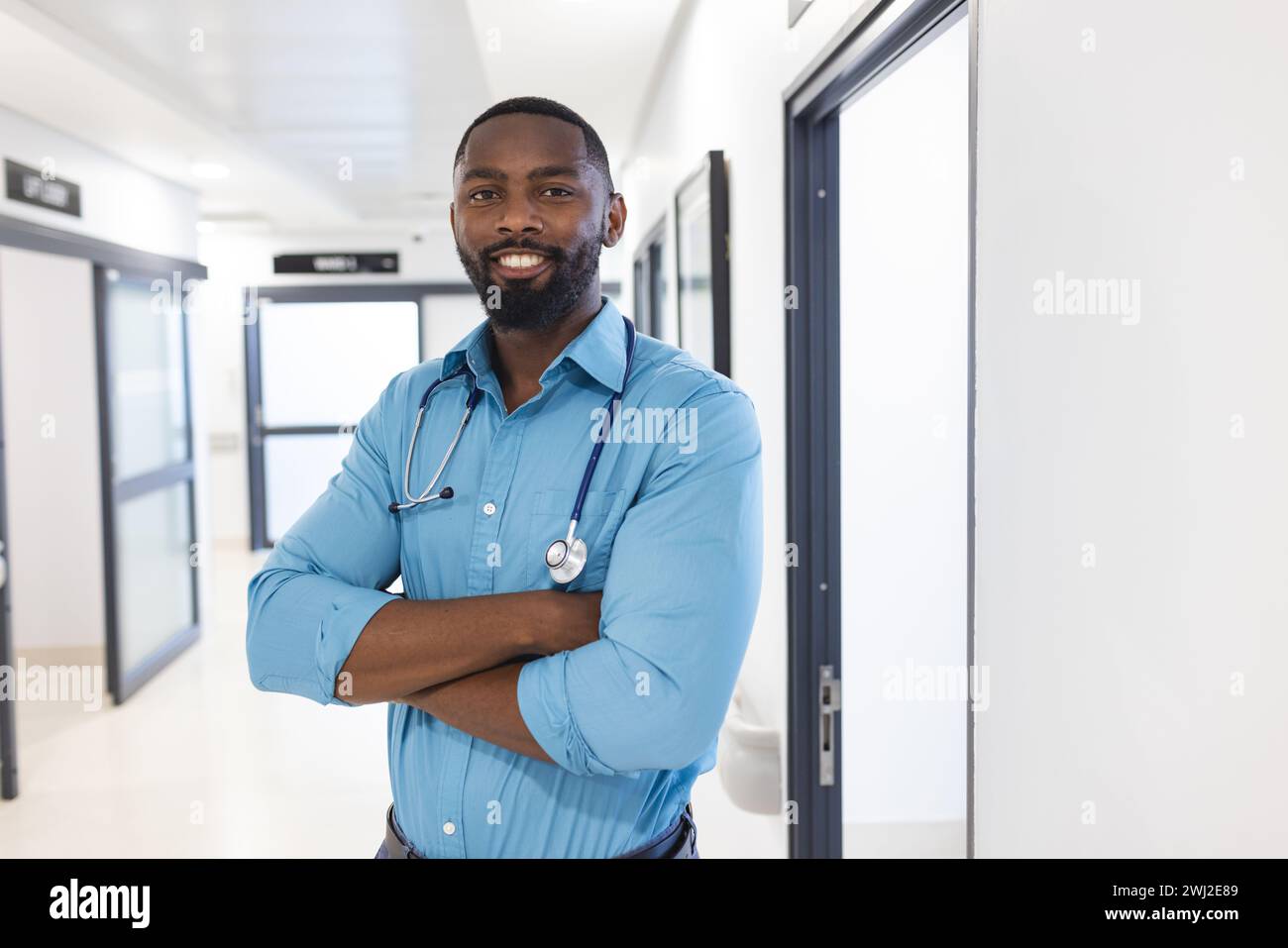 Retrato del médico masculino afroamericano feliz en el pasillo en el hospital, espacio de la copia Foto de stock