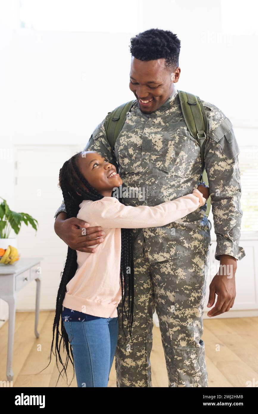 Soldado masculino afroamericano feliz abrazando a la hija en casa, espacio de copia Foto de stock