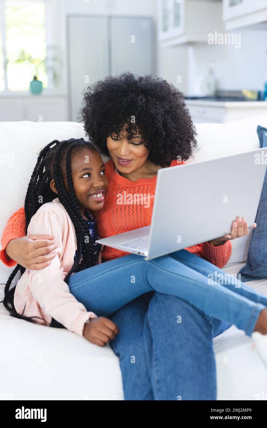 Feliz madre e hija afroamericana abrazando en el sofá y usando tableta en casa, espacio de copia Foto de stock