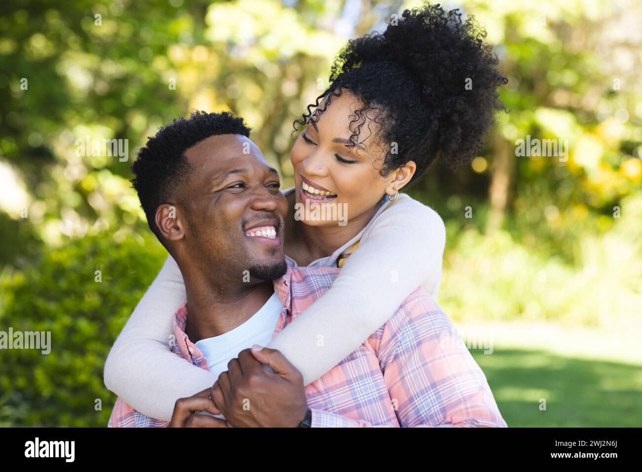 Feliz pareja afroamericana abrazando en jardín soleado, espacio de copia Foto de stock