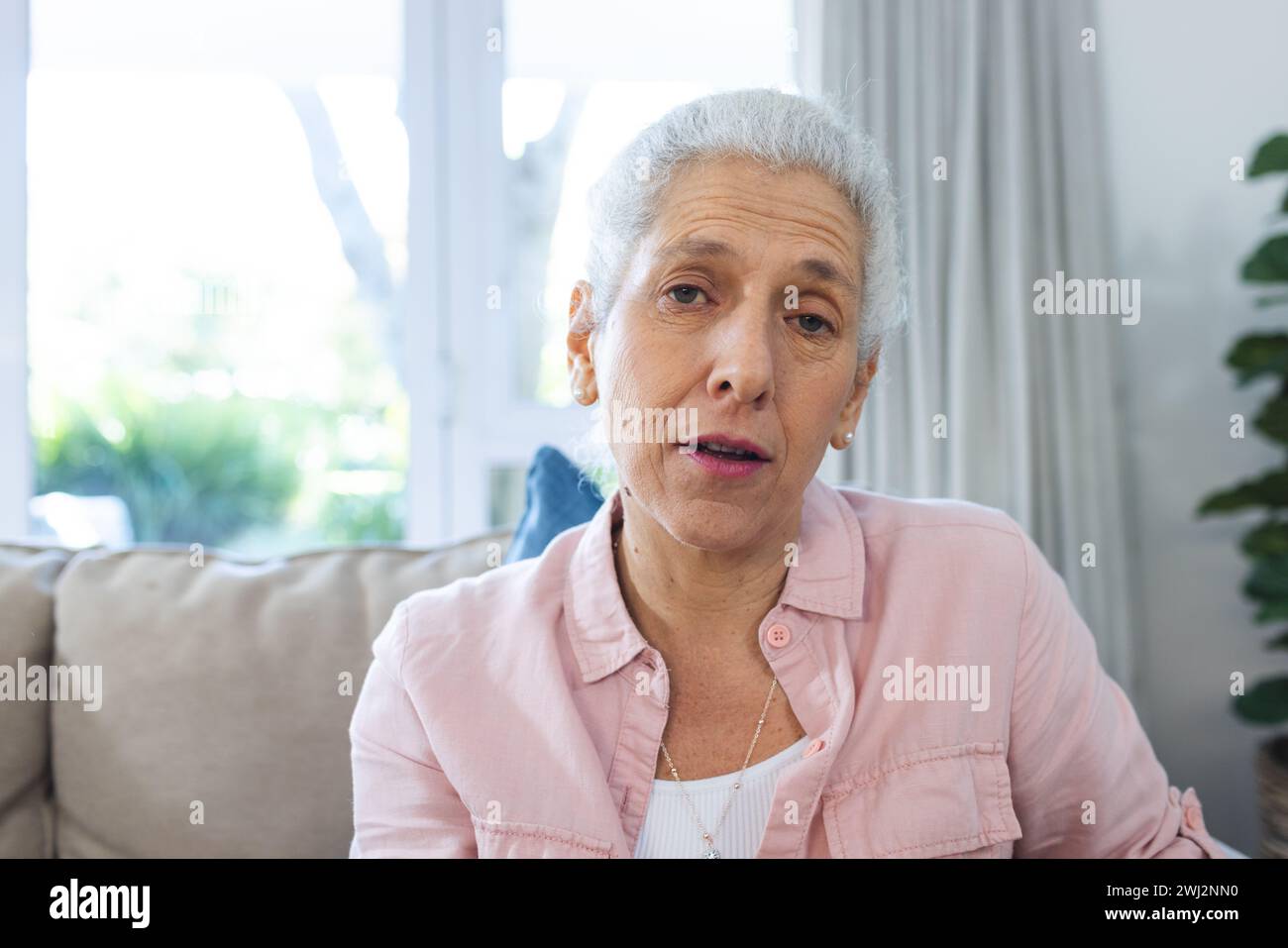 Mujer mayor caucásica haciendo videollamada en la sala de estar soleada Foto de stock