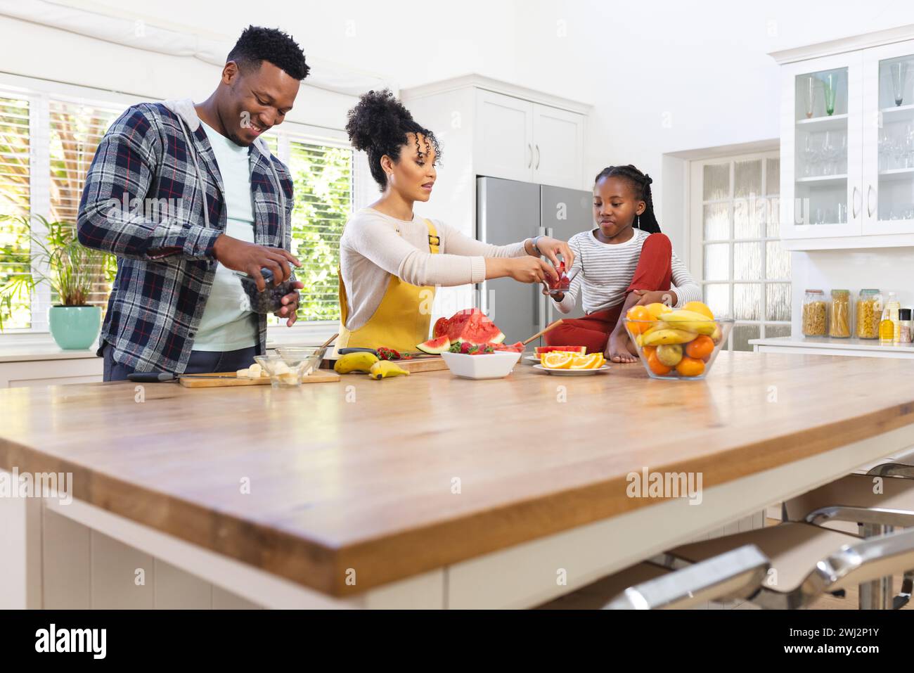 Familia afroamericana feliz que prepara bocadillo fresco de frutas en la cocina en casa, espacio de copia Foto de stock