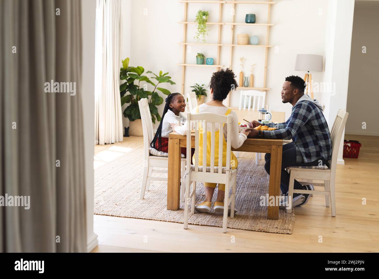 Familia afroamericana feliz desayunando en el comedor por la mañana en casa, espacio de copia Foto de stock