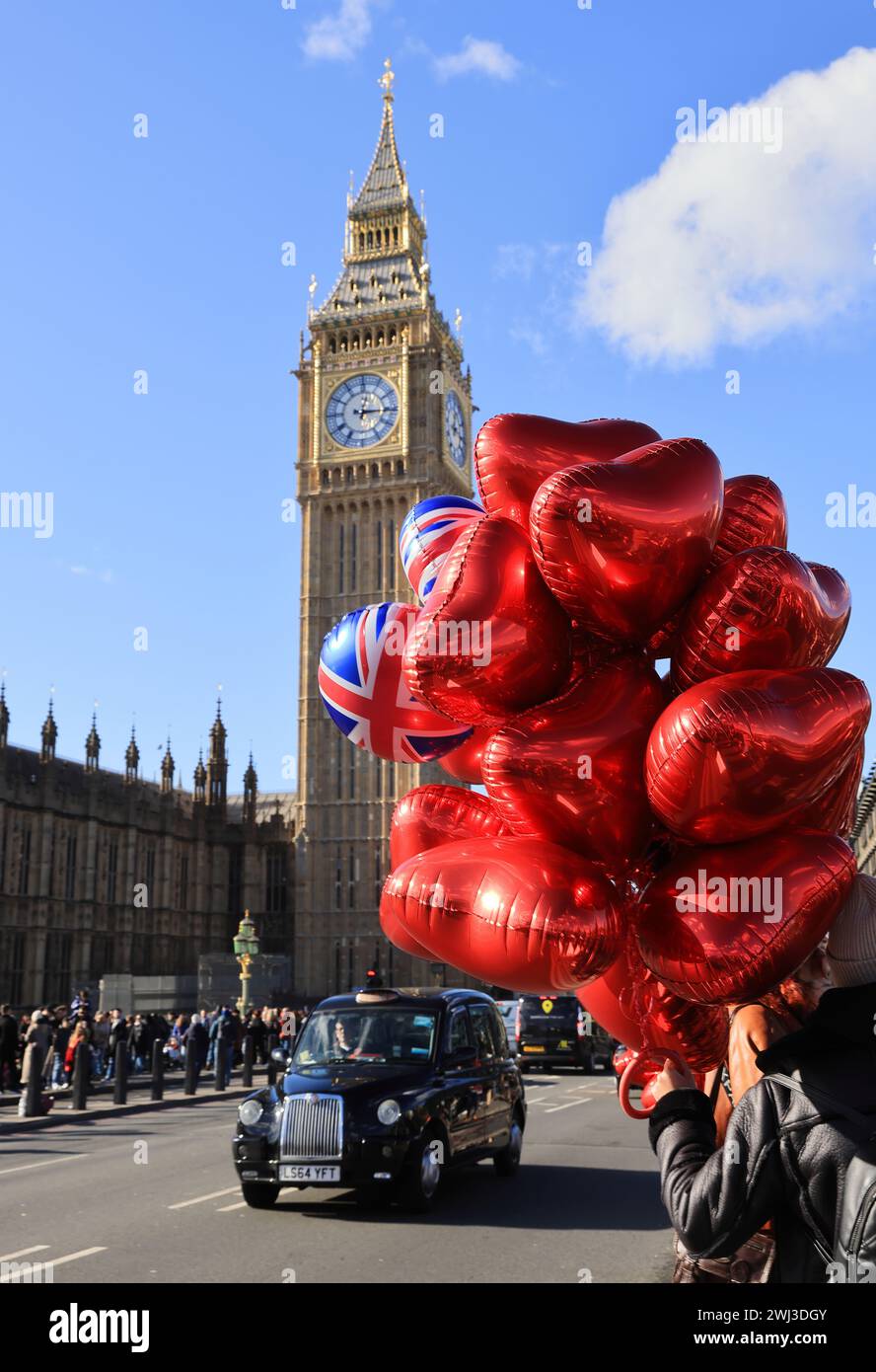 Globos de corazón rojo y de San Valentín a la venta en el puente de Westminster, con Big Ben detrás, en Londres, Reino Unido Foto de stock