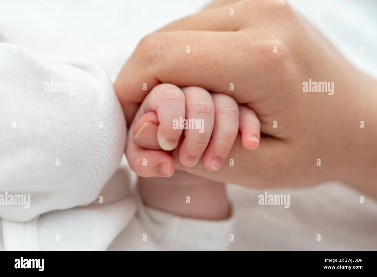 El delicado agarre del pulgar de la madre del recién nacido emana confianza. Concepto de conexión materna pura Foto de stock