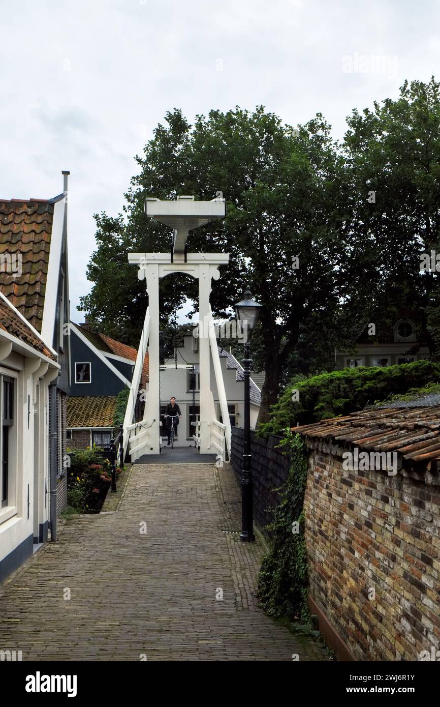 Ciclos de una persona a través de un puente levadizo en el callejón Kwakelsteeg en la zona del casco antiguo de la ciudad de Edam, Holanda Septentrional, en los Países Bajos. Foto de stock
