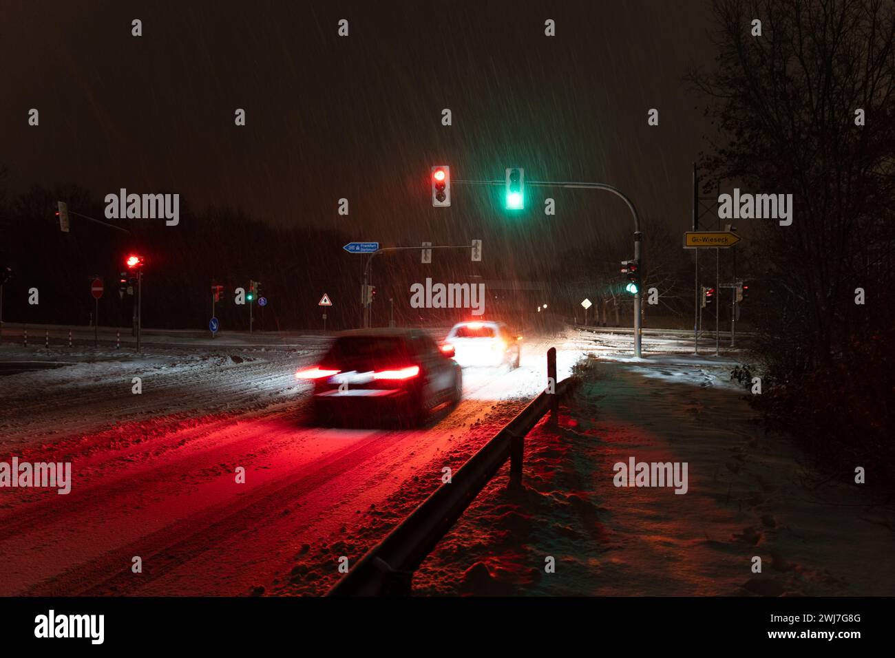 Dos coches conduciendo sobre la intersección en una tormenta de nieve por la noche en giessen, alemania Foto de stock