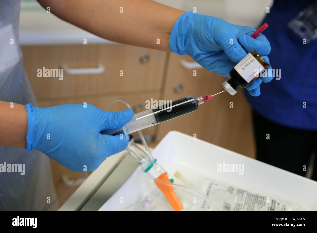 Enfermera que prepara la solución de Ferinject listo para administrar una infusión de hierro por vía intravenosa a un paciente en el Hospital Surrey Inglaterra Foto de stock