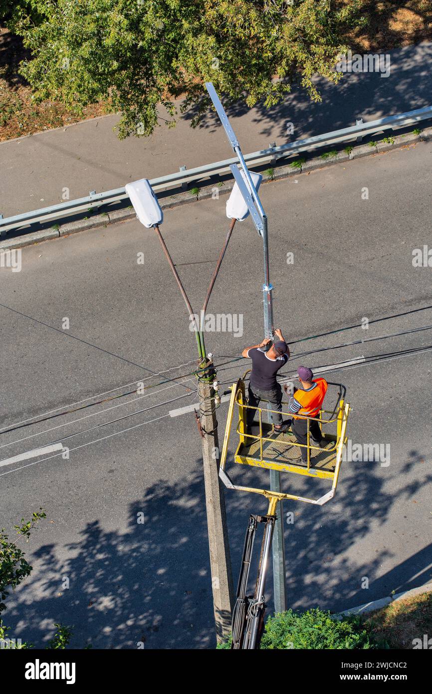 Los instaladores de trabajadores en un elevador neumático de automóvil están instalando una nueva lámpara de calle y desmantelando la antigua. Foto de stock