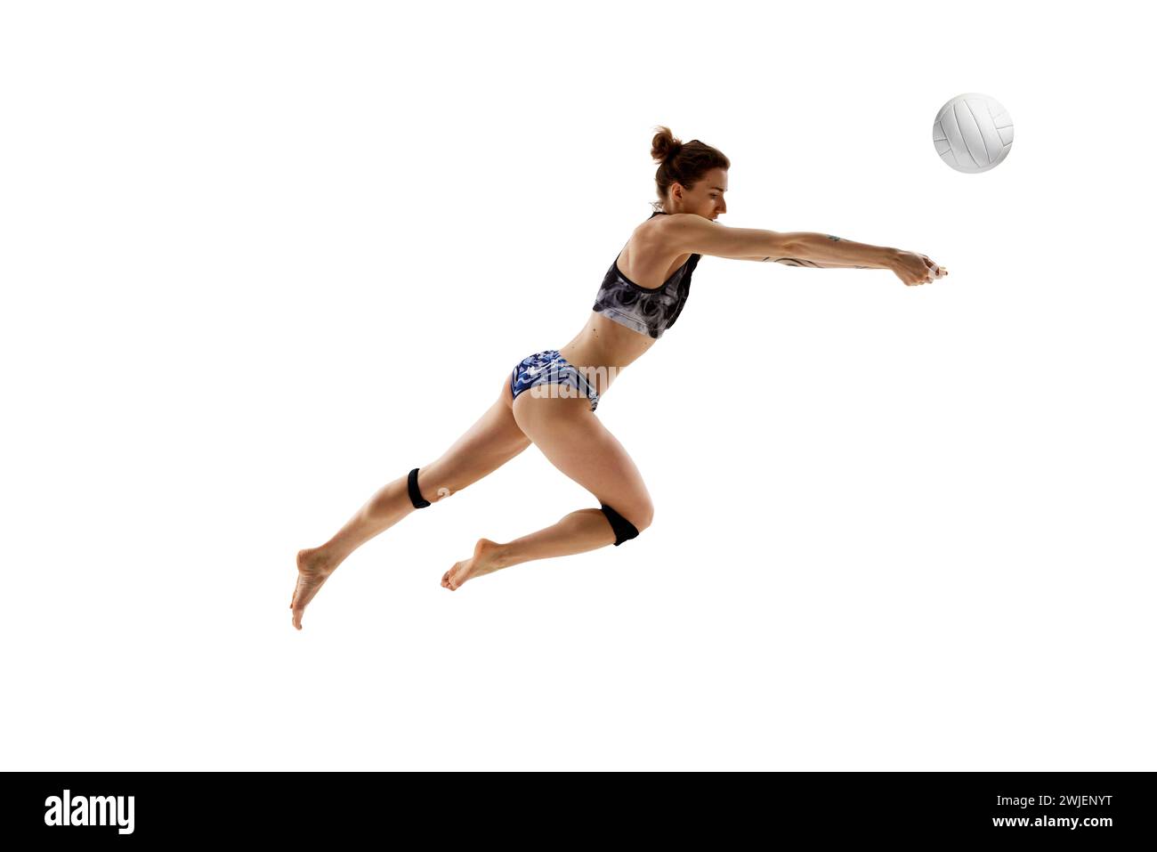 Mujer competitiva, jugador de voleibol experto en acción centrado en la pelota para servir el pase perfecto contra el fondo blanco del estudio. Foto de stock