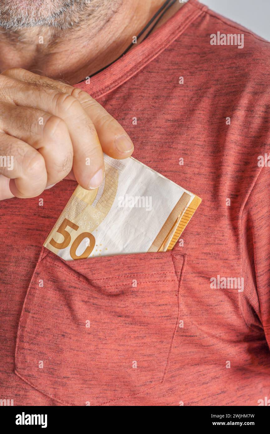 Primer plano de hombre poniendo billetes de euro en su bolsillo rojo de la camiseta Foto de stock
