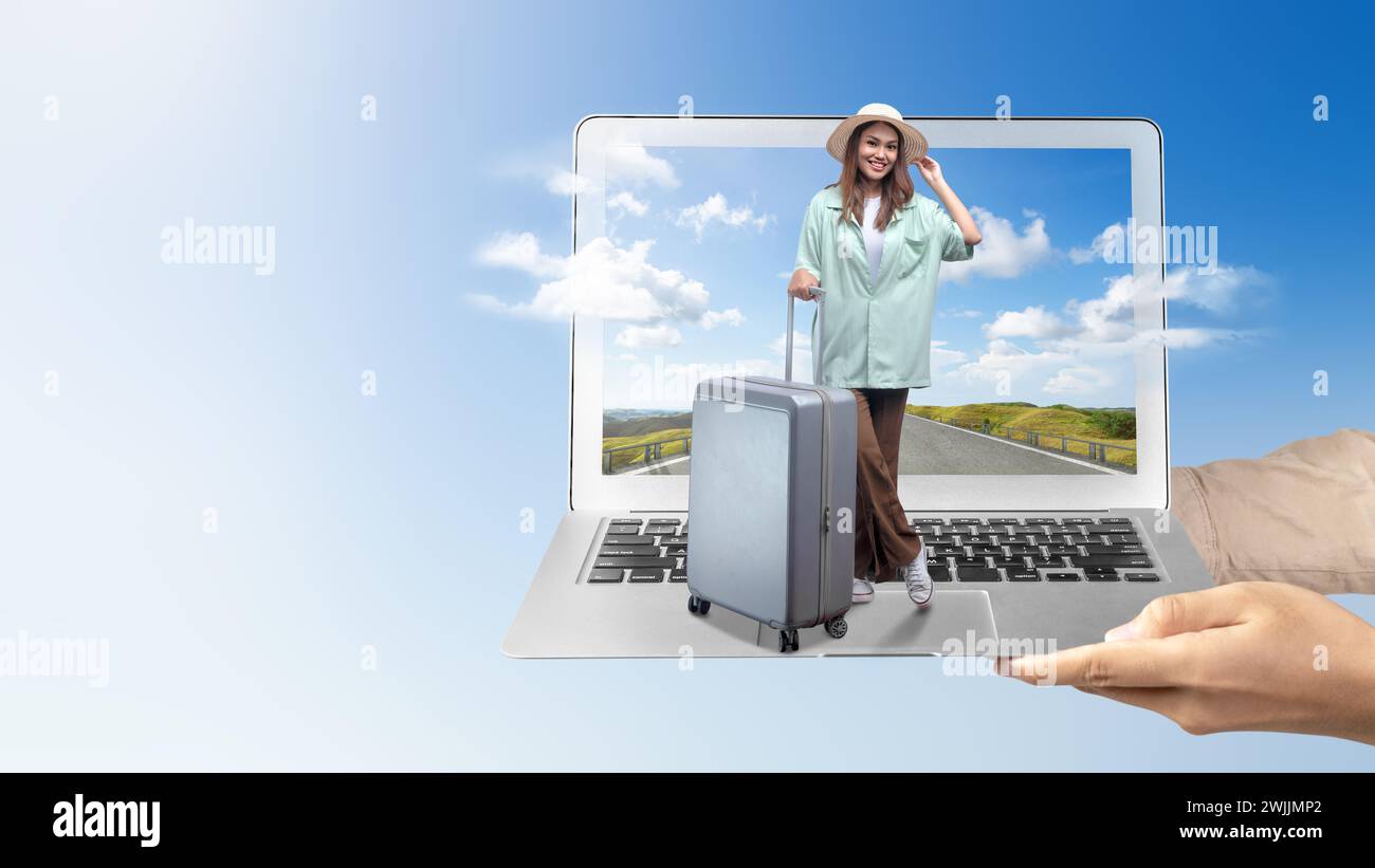Una mano humana sosteniendo un ordenador portátil con una chica asiática en un sombrero y una maleta con una vista de la colina y el cielo azul en la pantalla del ordenador portátil. Concepto de viaje Foto de stock