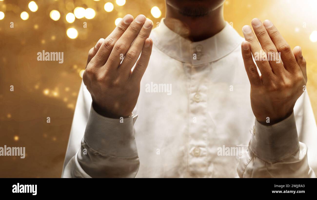 El hombre musulmán levantó las manos y oró a Allah con un fondo de luz borrosa. Concepto musulmán Foto de stock