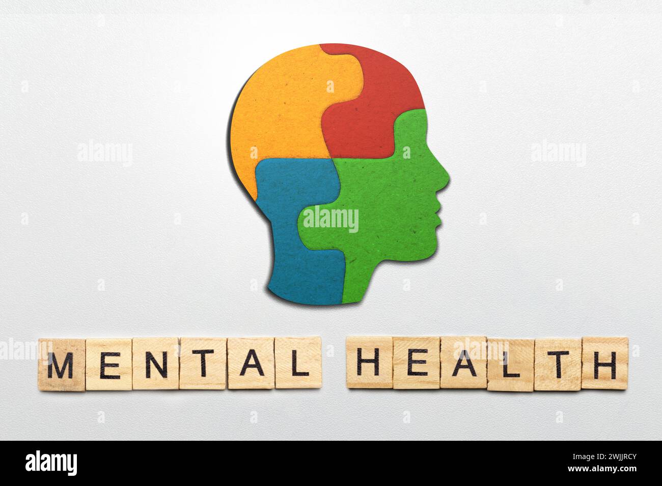 Un rompecabezas de cabeza colorido con texto de salud mental está en un fondo de color. Concepto de salud mental Foto de stock