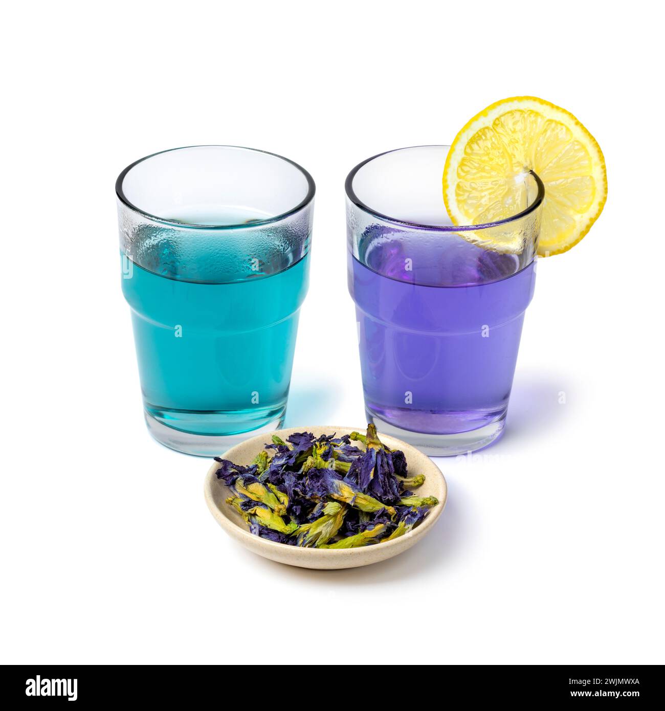 Vasos con té de flor de guisante de mariposa azul y púrpura con flores de té de guisante de mariposa seca y limón se cierran aislados sobre fondo blanco Foto de stock