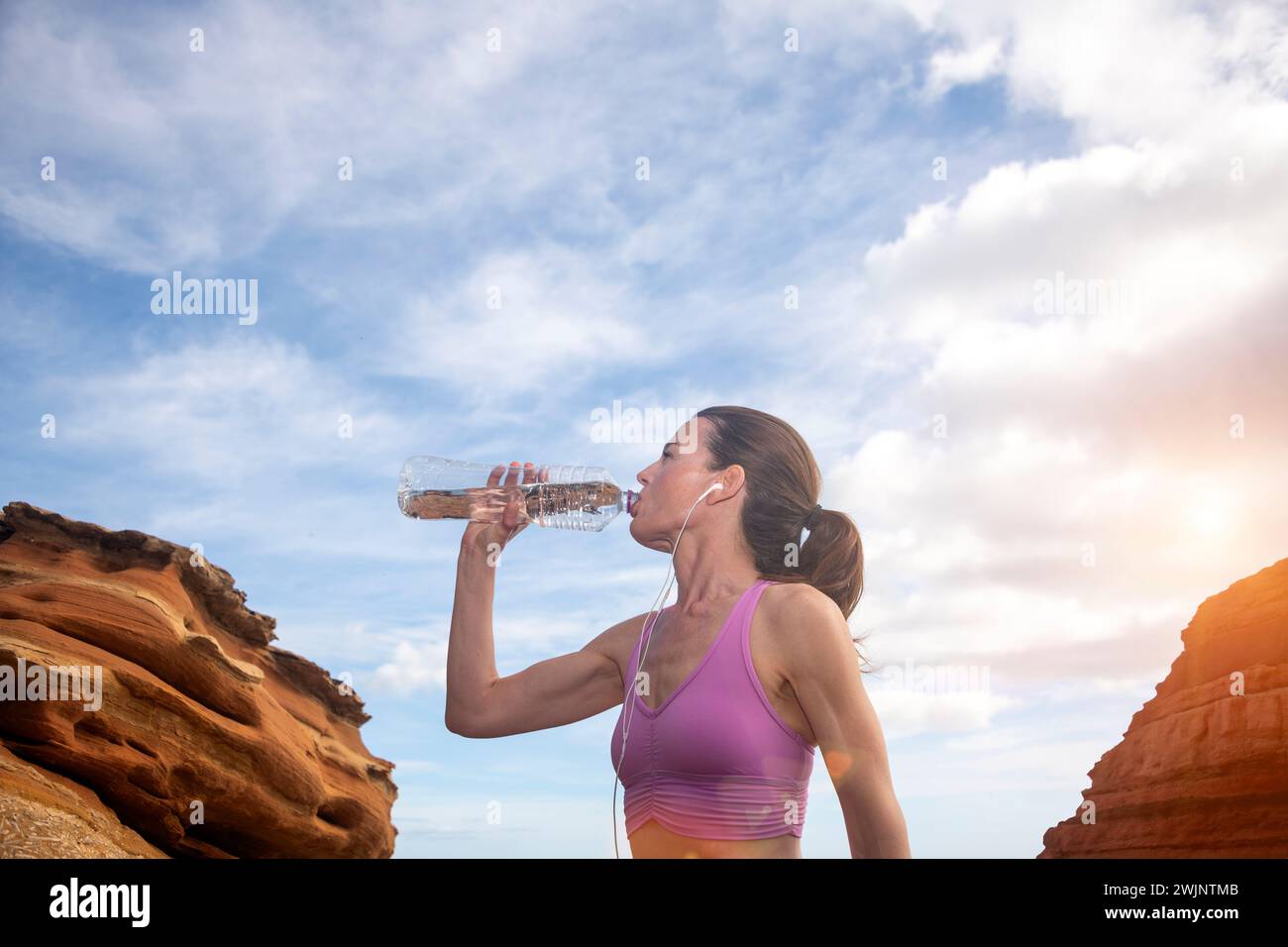 mujer deportiva bebiendo agua de una botella, sedienta después del ejercicio. Foto de stock