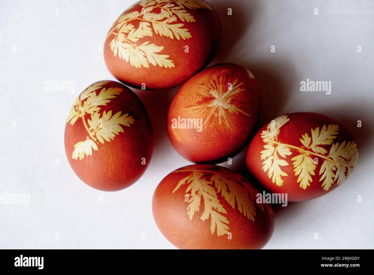 Huevos rojizos adornados con diseños de hojas amarillas. Foto de stock
