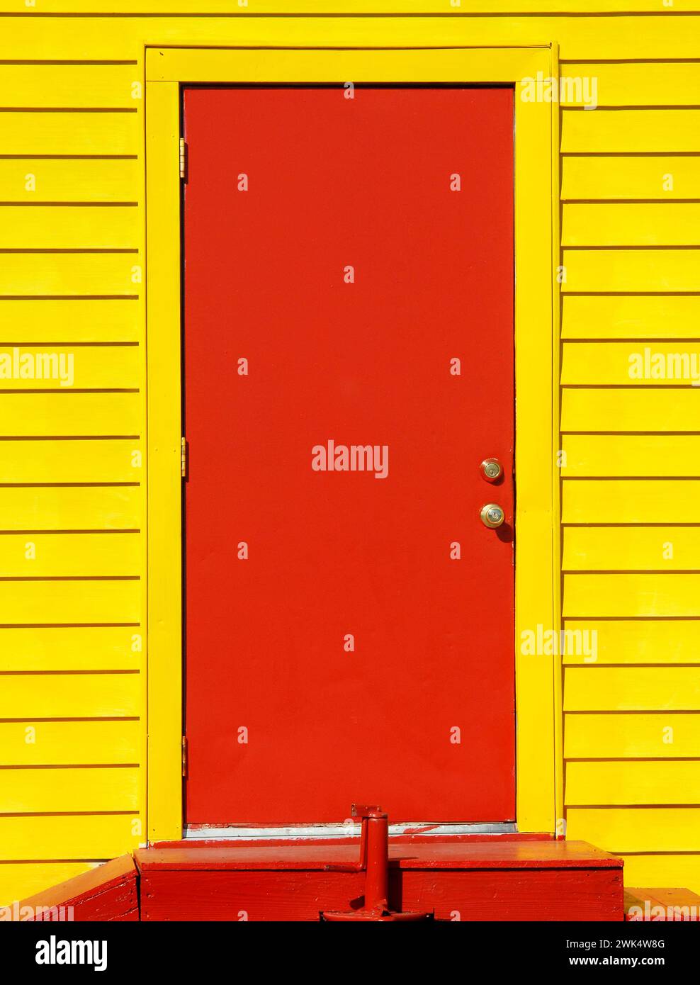 La imagen de fondo muestra una puerta de madera roja en un edificio amarillo brillante. Escaleras rojas conducen a la entrada. Foto de stock