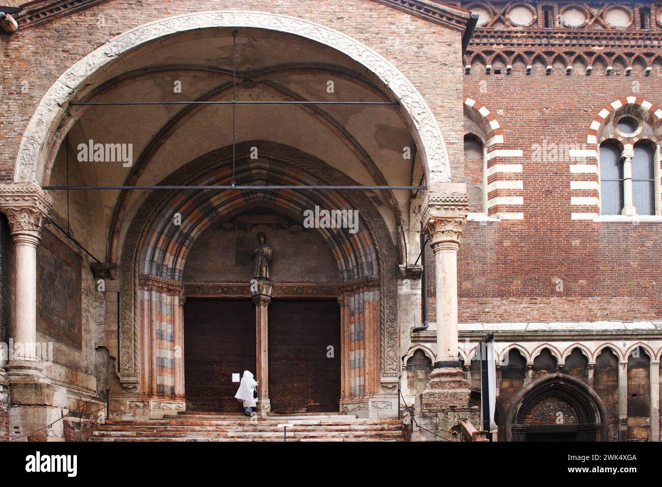 Detalles de la calle en el casco antiguo de Verona, mujer entrando en la iglesia Foto de stock