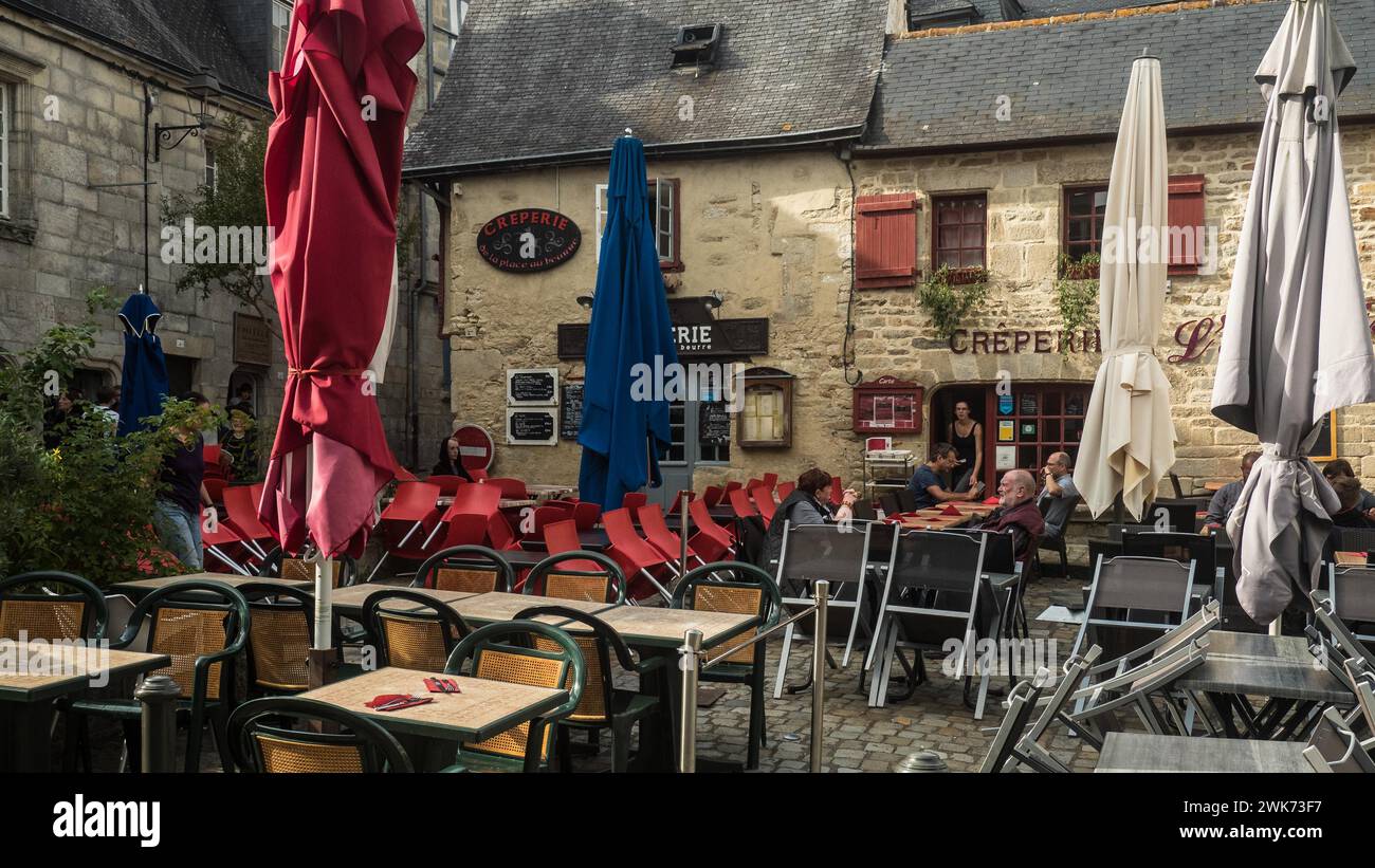Una cafetería vacía con sillas rojas y sombrillas cerradas en un callejón adoquinado Quimper Bretagne Foto de stock