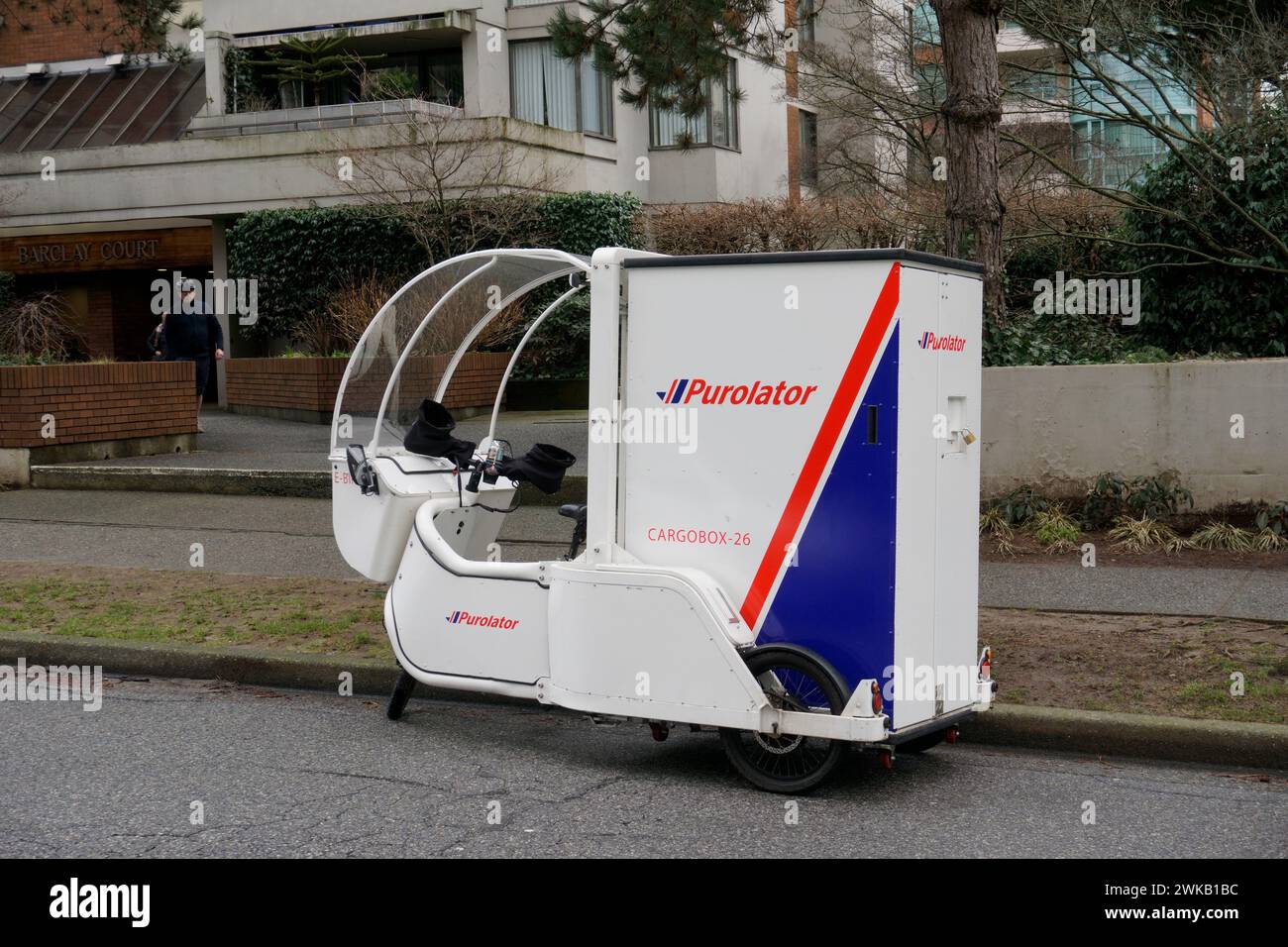 Una bicicleta eléctrica de entrega de carga Purolator estacionada en una calle residencial en Vancouver, BC, Canadá Foto de stock