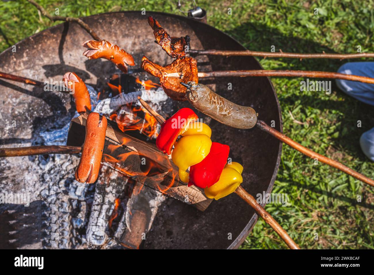 Barbacoa al fuego. Salchichas, pimienta y calefacción de carne por encima de la fogata al aire libre. Foto de stock