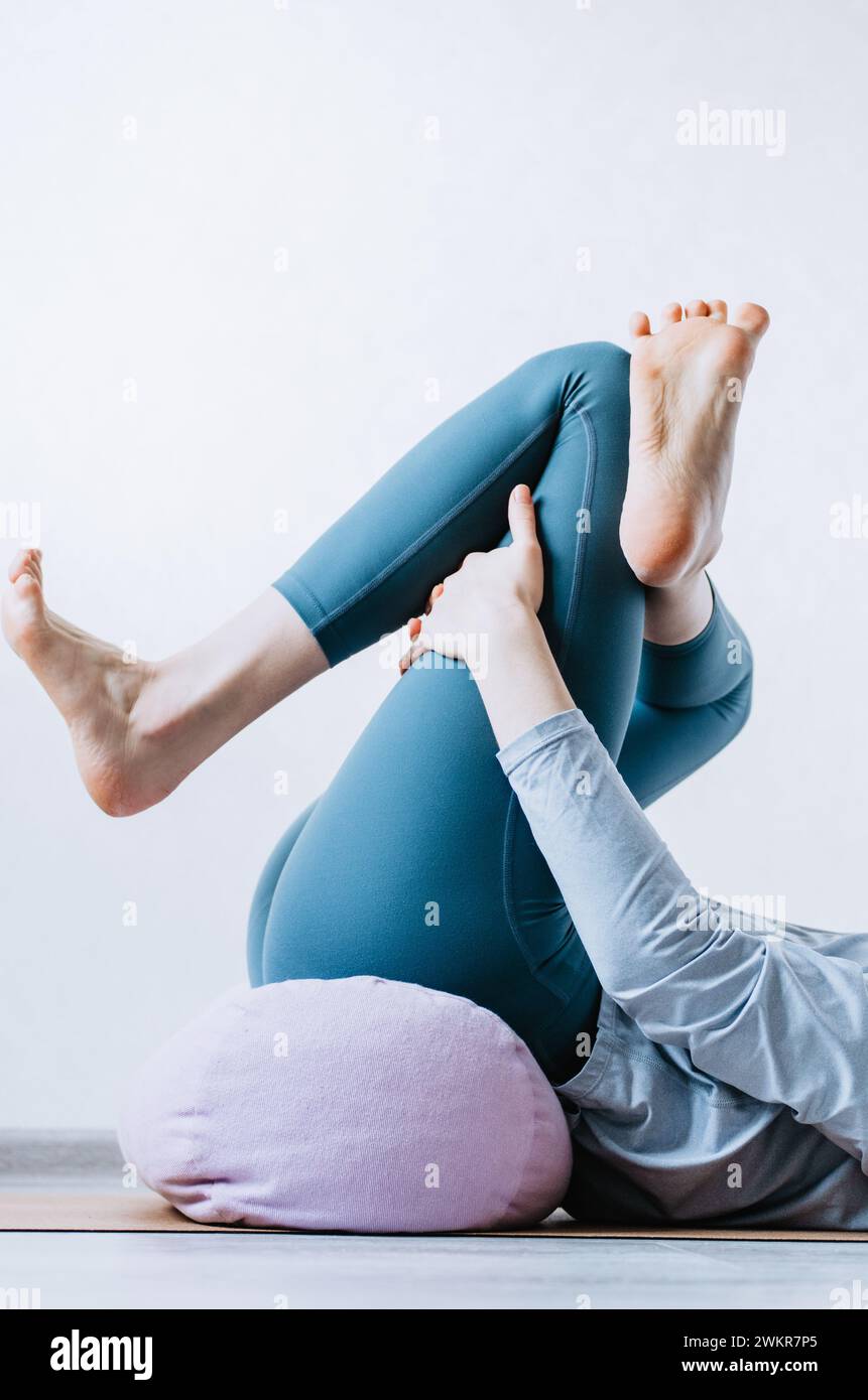 Mujer haciendo yin yoga ejercicios pasivos de estiramiento de cadera en refuerzo Foto de stock