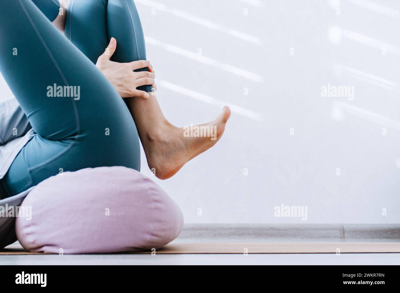 Mujer haciendo yin yoga ejercicios pasivos de estiramiento de cadera en refuerzo Foto de stock