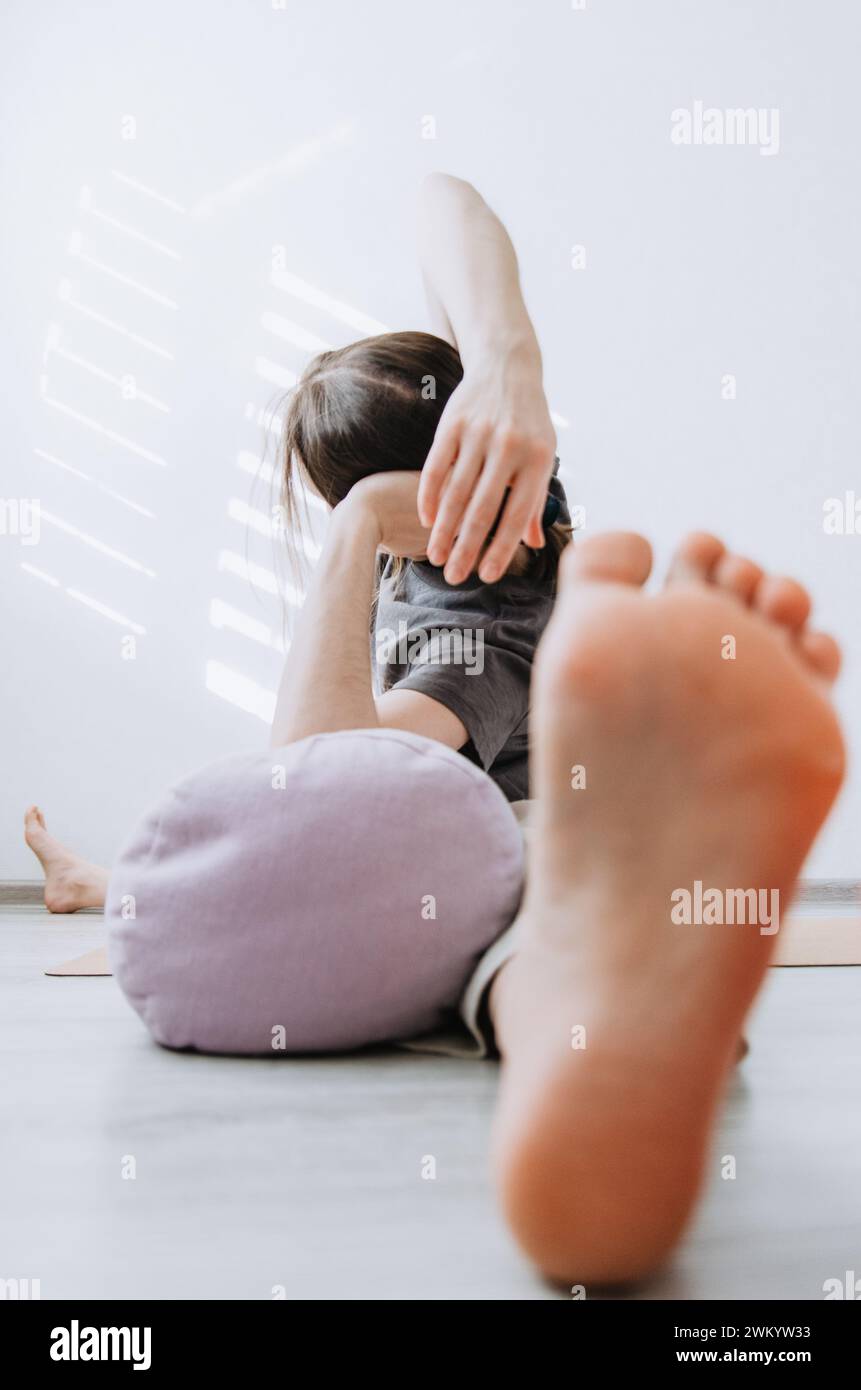 Mujer en ropa casual practicando yin yoga de patas anchas de flexión lateral pose con un refuerzo Foto de stock