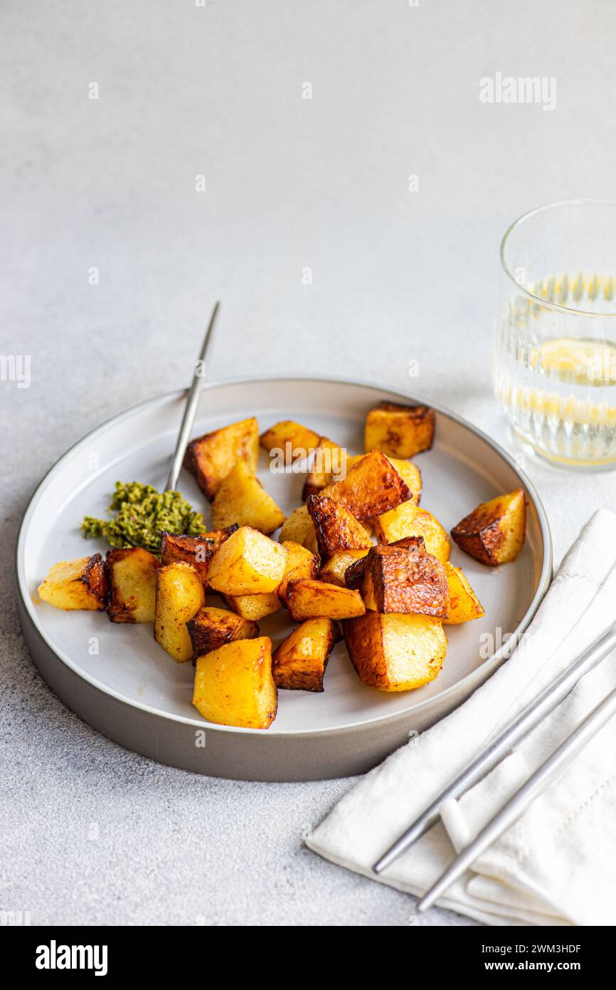 Patata frita con salsa de pesto servida en el plato con vaso de agua con rodaja de limón Foto de stock