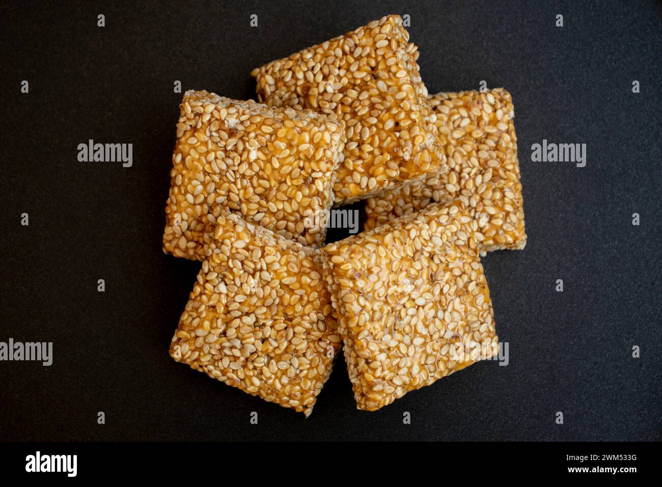 Til chikki sobre fondo gris negro. Til chikki es un plato de dulces indios hecho con jaggery y sésamo. Festival indio makar sankranti especial dulce Foto de stock