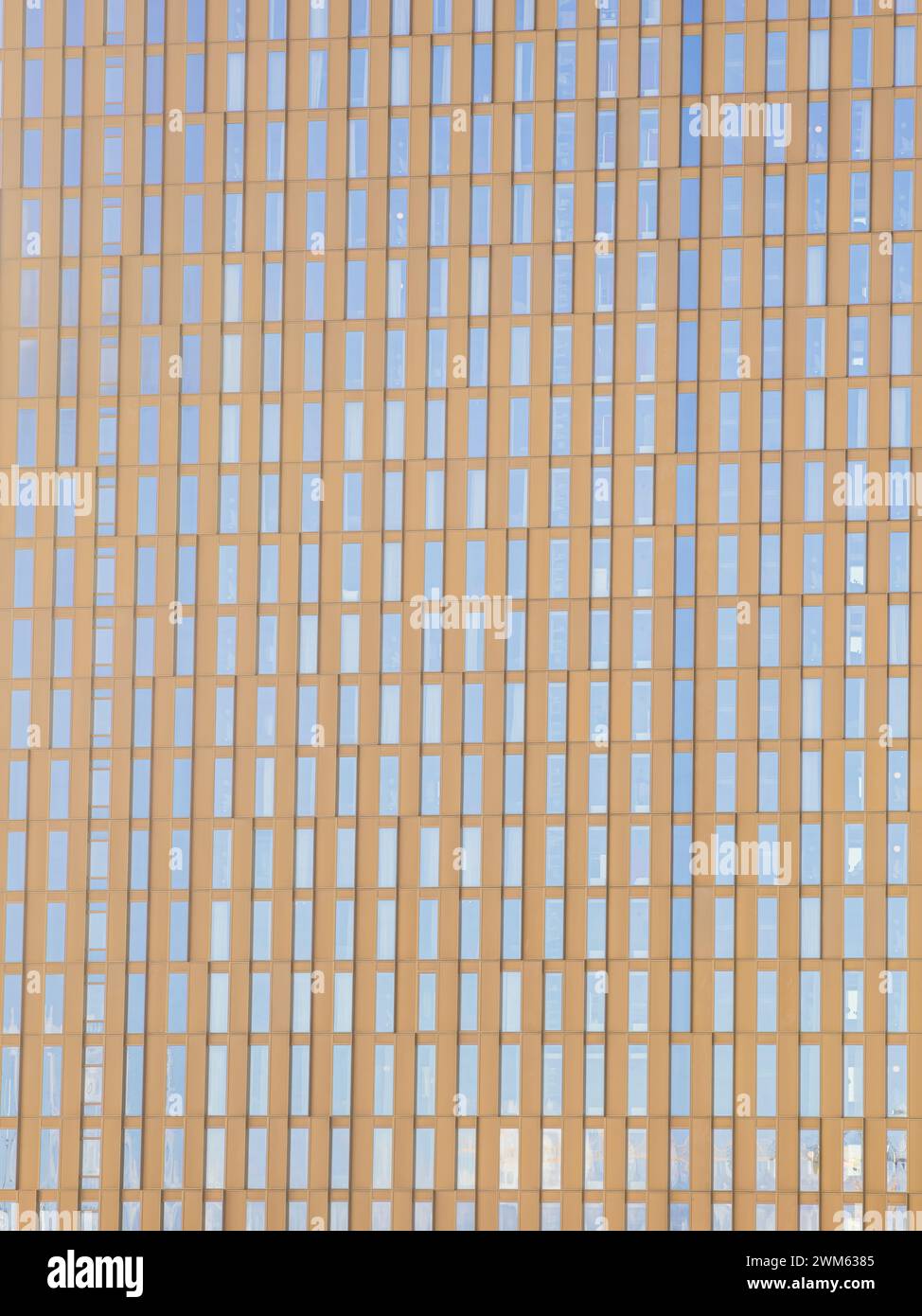 Una vista de cerca de un moderno edificio de oficinas en Gotemburgo, Suecia, mostrando un patrón simétrico de ventanas que reflejan el cielo azul. La dorada h Foto de stock