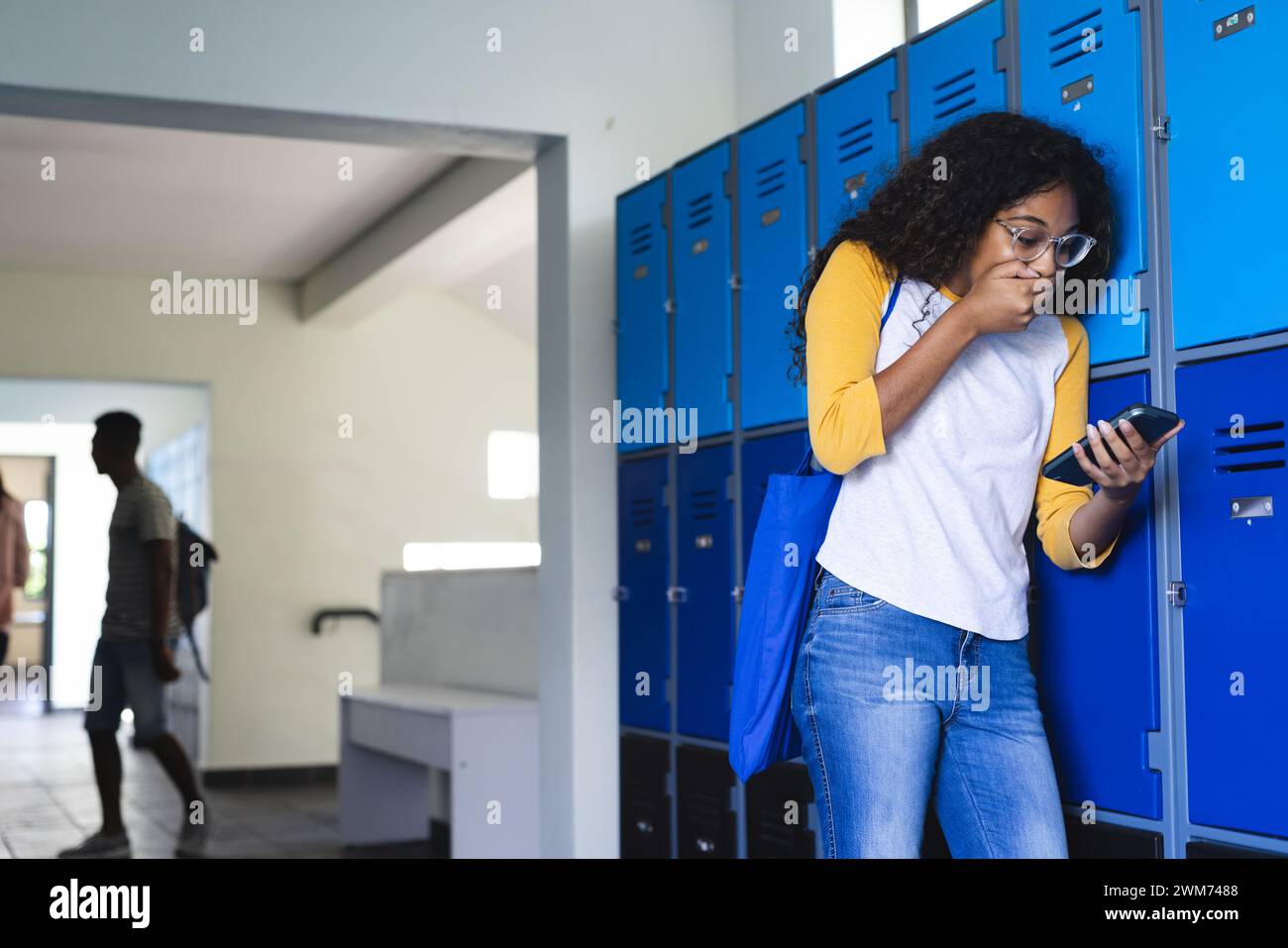 Niño biracial adolescente camina en un pasillo de la escuela secundaria, con espacio de copia Foto de stock