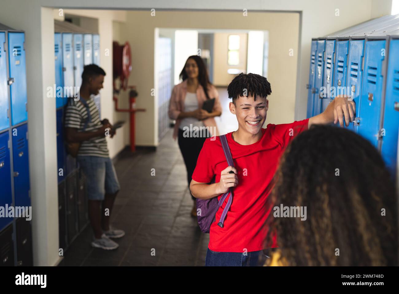 Adolescentes niños y niñas biraciales en un pasillo de la escuela secundaria Foto de stock